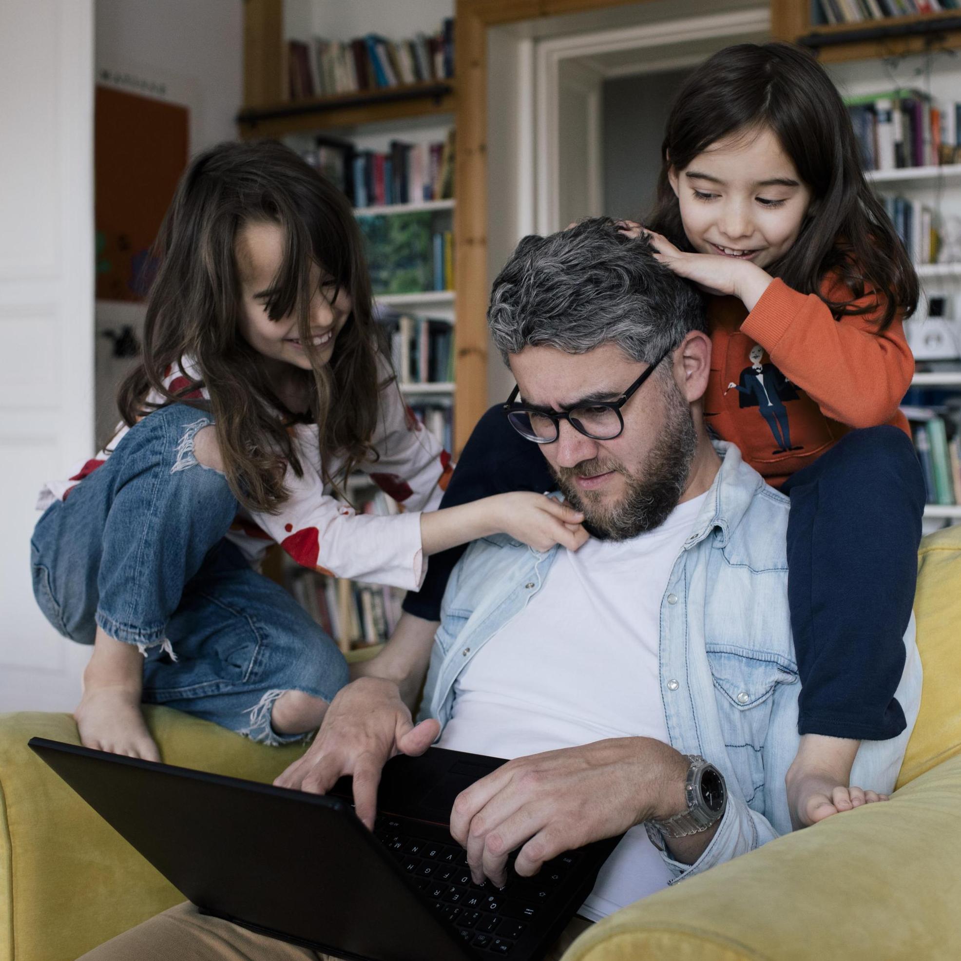 Dad looking at a laptop together with his kids