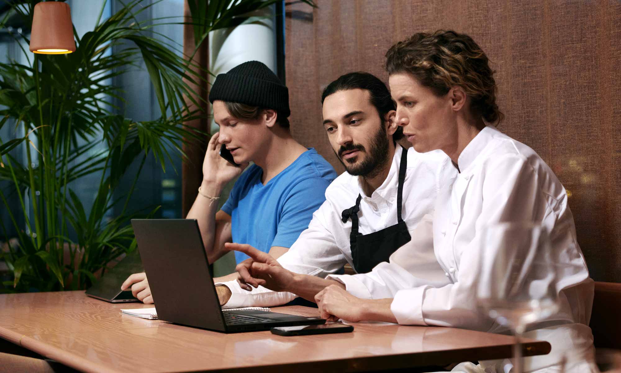 Restaurangpersonal har möte vid en bord med en laptop